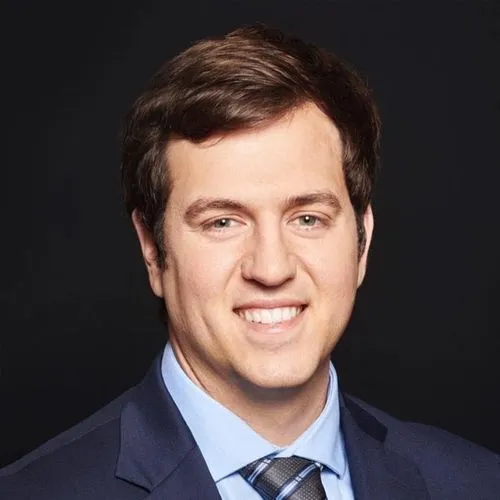 A man in suit and tie smiling for the camera.