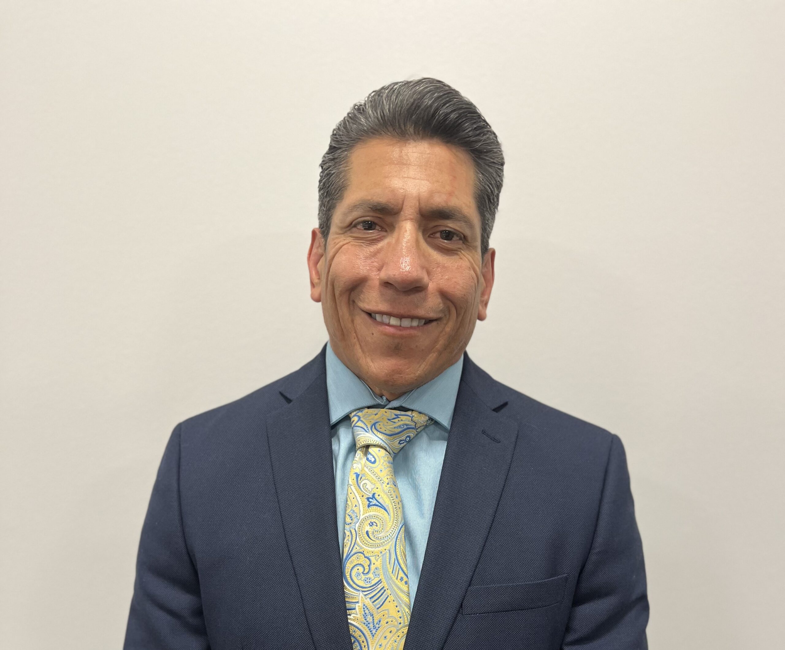 A man in a suit and tie standing with his hands crossed.