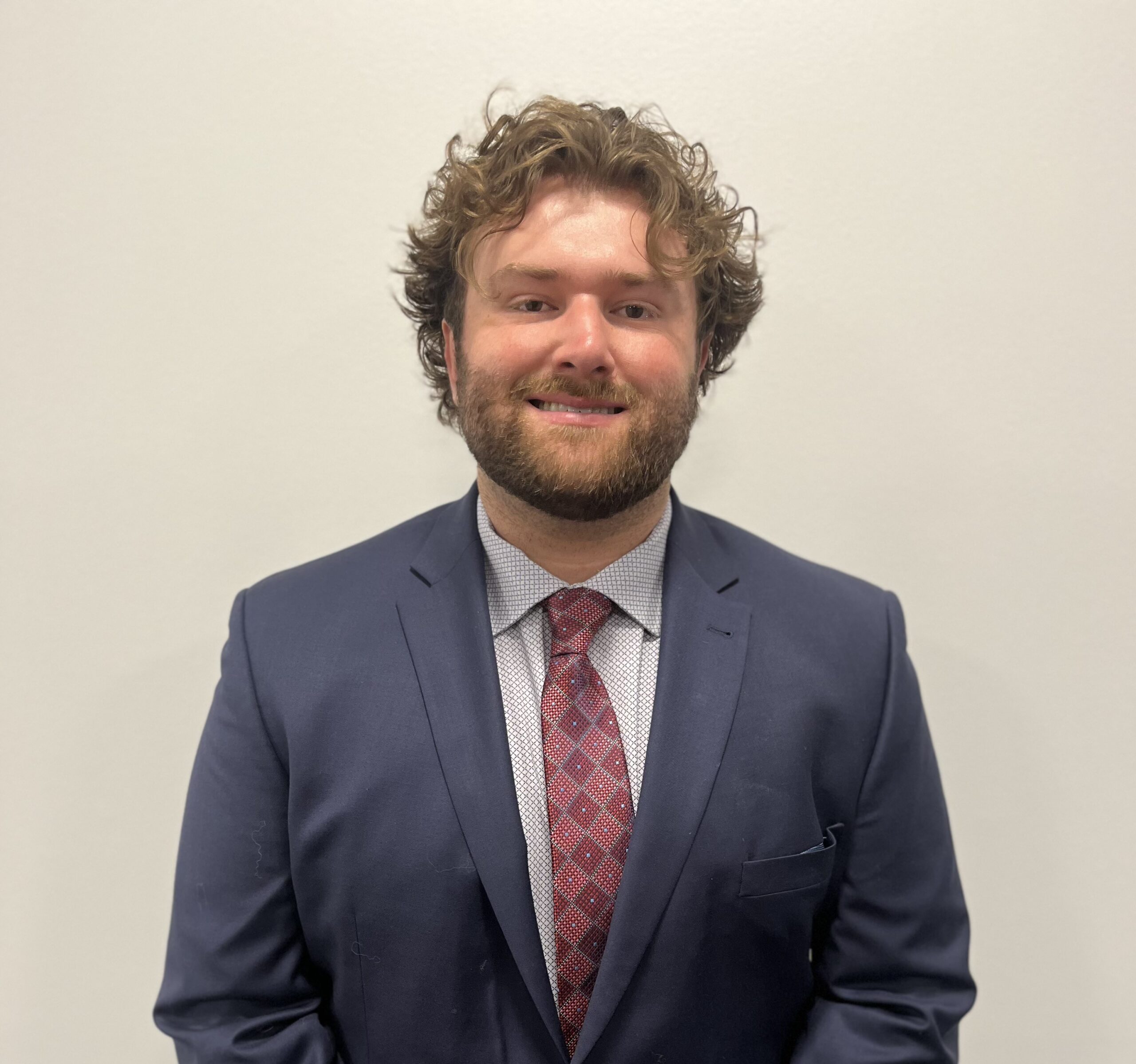 A man in a suit and tie standing next to a wall.